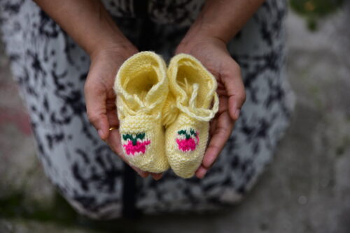 A woman with colorful child socks on her hands, concept of a woman expecting child in her life